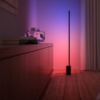 A Philips Hue Signe gradient floor lamp washes a wall in purple and pink tones of smart light.