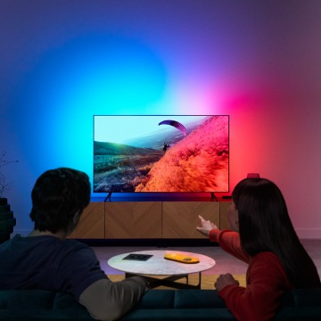 Een stel geniet van LED-licht voor tv, waarbij kleuren gesynchroniseerd worden met het scherm.